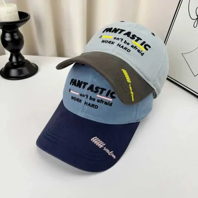 Grey and navy baseball caps with embroidered lettering on a table