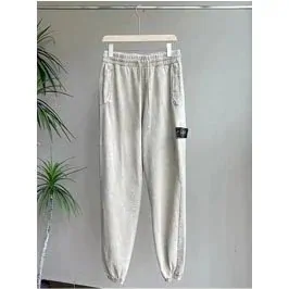 Light grey tapered joggers on a hanger beside a potted plant